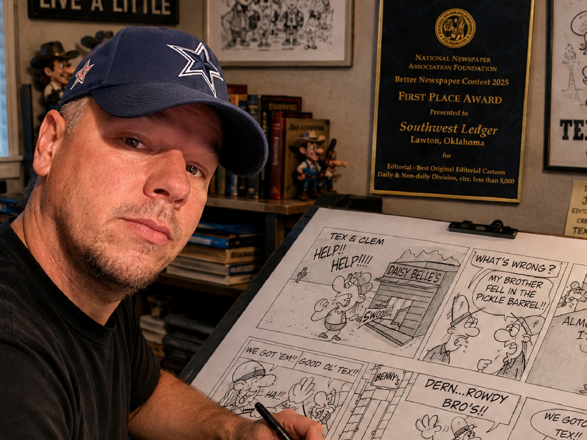 Jim Cox at his drawing table in his studio, surrounded by his NNAF First Place award and Tex & Clem artwork